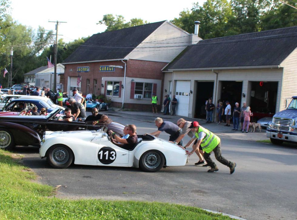 Men push carVolunteers push Steve Katz\u2019s 1959 Triumph TR3 into a parking spot after the classic car overheated near the end of the parade.