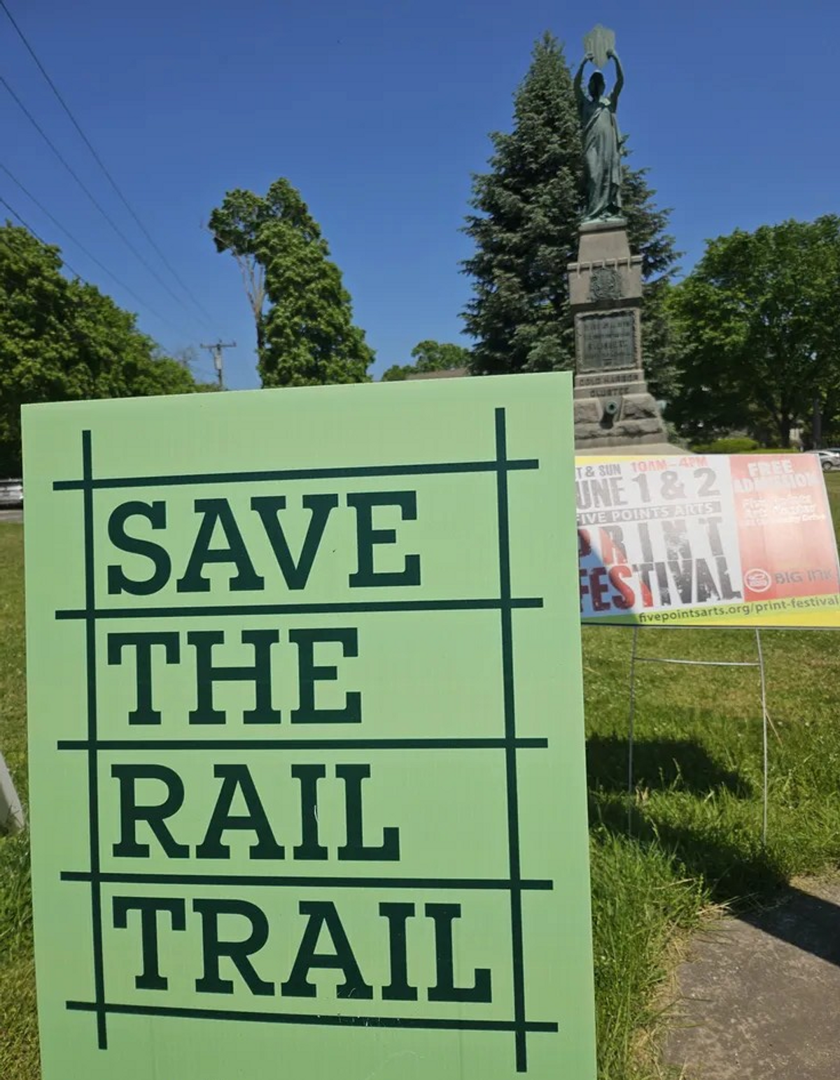Behind 'Save the Rail Trail' signs