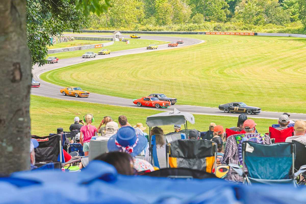 Spectators watch historic race cars race around the track