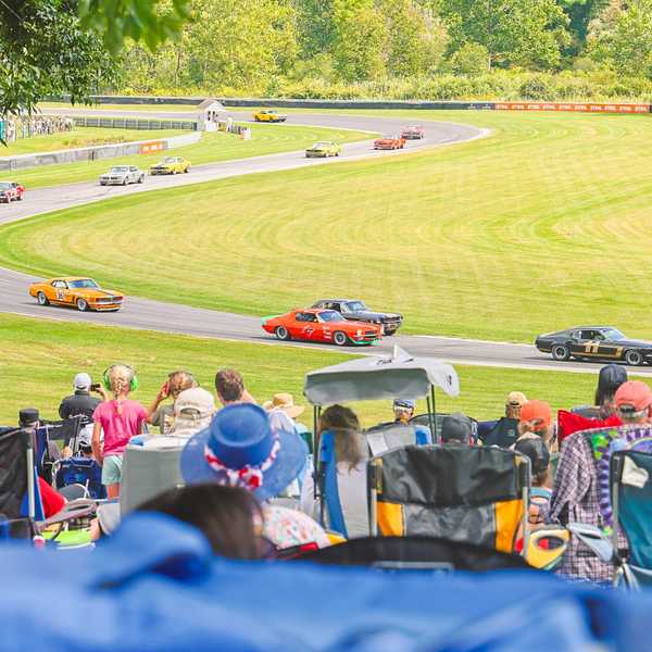 Spectators watch historic race cars race around the track