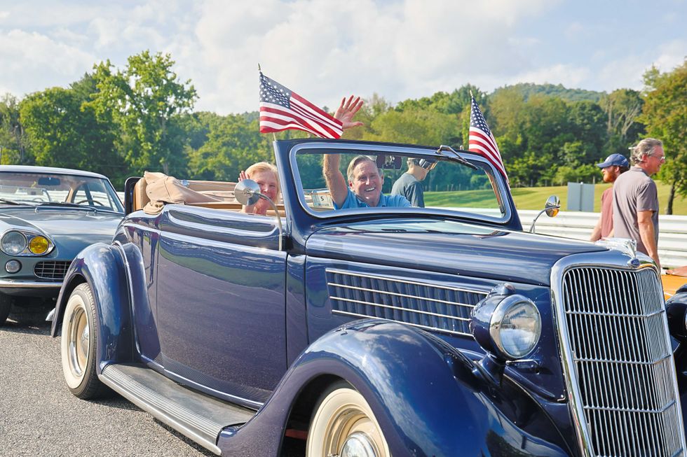Todd Mackenzie and his wife give a wave in their navy blue 1935 Ford Roadster.