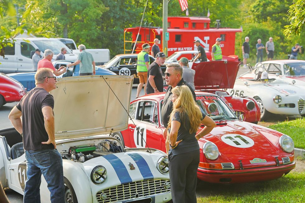 \u200bThree people take a closer look under the hood of a classic car following the parade